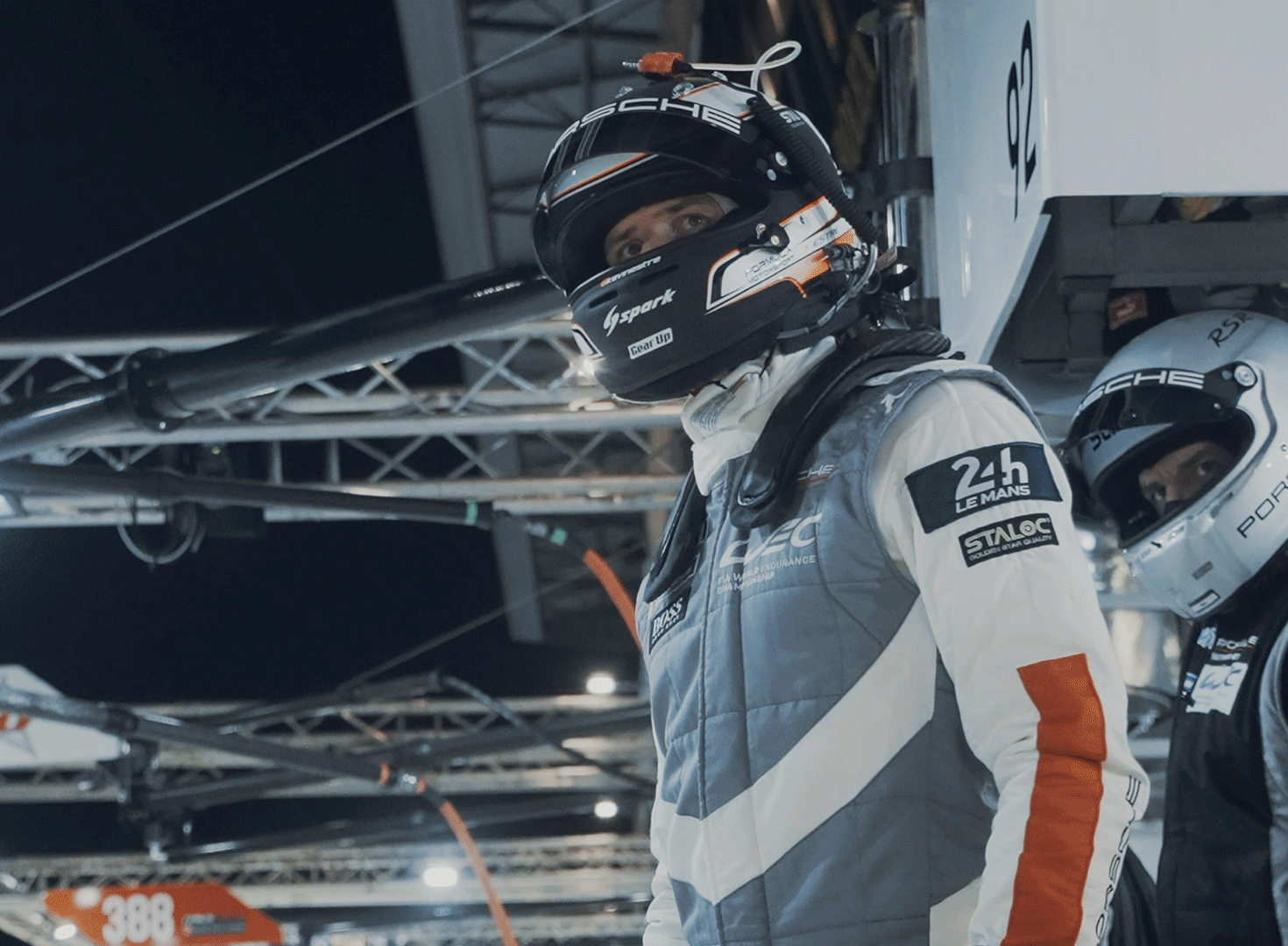 Man in 24 Hour Le Mans racing gear and helmet looks toward track